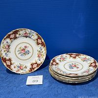 Set of six Tuscan Windsor floral design china plates with gold trim, stacked and one plate displayed upright.