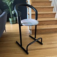 Front angle view of Amisco Memphis style stool chair showing tubular black curved frame and pastel plaid seat
