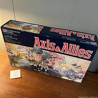 Front and angled view of the sealed Axis & Allies board game box showing detailed artwork and seller's lot number.