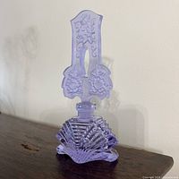 Front view of the purple Czech Bohemian glass perfume bottle with stopper on a wood table.