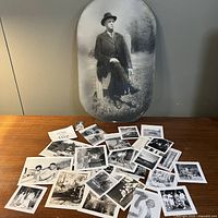 Large oval Edwardian-era portrait of a man seated outdoors, surrounded by a scattered collection of smaller black and white photographs mostly showing people and nature scenes.