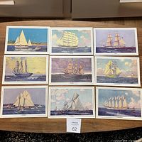 Nine vintage boat prints by Lorne K. Smith arranged in a grid on a table, showing various types of sailing vessels and some damage/staining on two prints.
