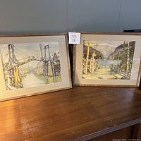 Both framed prints side by side showing bridge and totem pole scenes, wood frames with chips