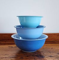 Three nested Pyrex mixing bowls from side angle showing graduated sizes and blue exterior paint