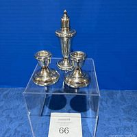 Front view of two sterling silver weighted candlesticks and one sterling silver shaker.