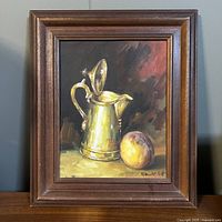 Full view of the original framed still life painting showing the coffeepot and peach on a neutral wall surface.