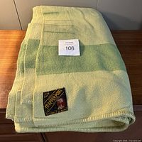 Folded jadite green wool blanket with Trapper Point label visible on corner.