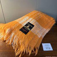 Folded vintage Eatons throw blanket showing black woven label with bagpiper logo and brand name.