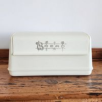 Front view of vintage Lustro-Ware bread box closed, showing 'BREAD' lettering on roll-top lid and creamy off white finish.