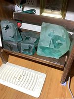 Group photo showing the five green frosted carved glass sculptures with various animal designs displayed on a wooden shelf.