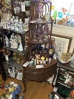 Full view of the vintage wooden corner cabinet with shelves and displayed items, showing overall shape and condition.