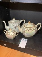 Three-piece ceramic set: two teapots and one sugar dish, displayed on shelf with sale tag