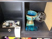 Photo showing the shadow box with mineral collection on left and alabaster urn, ceramic turquoise urn, blue glass Mustang car, and metal trivet on right