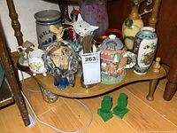 Full view of various vases and collectibles on wooden shelf including porcelain vase, blue glass flower vase, teapot, and figurines