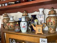 Overview of the top of cabinet holding multiple vases, urns, and collectibles with varied Asian-inspired decorative styles.