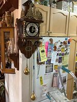 Wooden wall clock mounted on wall showing full view with two brass weights hanging