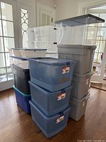 Stack of large plastic storage bins with lids in various colors