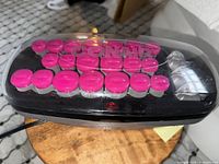 Conair hot rollers with pink rollers in black base on wooden table