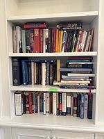 Full view of three shelves packed with an assortment of hardcover and paperback books of various sizes in good condition.