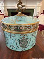 Closed pale turquoise porcelain canister with gilt chains and medallion motifs on table