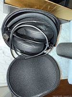 Black Beats over-ear headphones inside a soft case with cables visible.