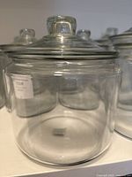 Close-up of medium-sized clear glass jar with matching lid, transparent with smooth edges and round knob on lid.