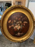 Large oval floral oil painting with ornate gold frame showing some cracking and a chip, signed 'Hardey'.
