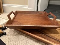 Stacked solid wood trays showing handles and wood grain