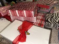 Stacked holiday-themed paper napkins in various patterns including red and white, plaid, and polka dot designs.