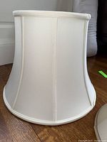Large white fabric lamp shade with rounded bell shape, smooth vertical panels and structured rim edges.