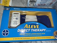 Aleve Direct Therapy wireless TENS device in original packaging, showing the device and remote control in blue and white colors with a yellow label.
