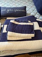 Folded navy and white striped quilt with matching sham and lumbar throw pillow on mattress