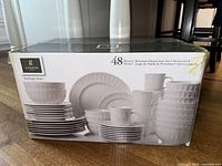 Box of Gibson Home 48 piece porcelain dinnerware set showing stacked bowls, plates, and mugs in white with a textured dot pattern.