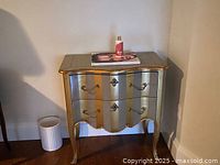 Front view of the painted side table showing two drawers, scalloped apron, curved silhouette and brass hardware