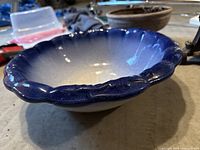 Close-up of large antique blue ceramic washing bowl with scalloped edges and gradient color.