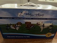 Original packaging of Walkin' Wheels adjustable wheelchair for pets showing three dogs using different color wheelchair versions on front of box