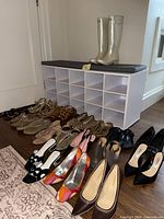 Front view of assorted shoes arranged on floor with white cubby organizer and gray cushion in background