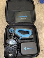 Theragun Elite in open carrying case with charger dock and attachments