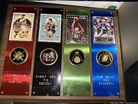 Full view of wooden plaque with four sports cards and nameplates for Ted Williams, Bobby Orr, Larry Bird, Tom Brady.