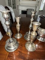 Four silver candlesticks—two tall and two shorter—on dining table