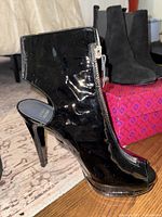 Patent leather peep‐toe ankle bootie showing front zipper and stiletto heel