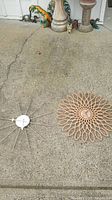 Two clocks on concrete surface: a beige sunflower style Karlsson clock and a metal starburst Verichron clock.