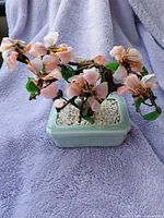 Full view of the bonsai tree showing pink glass cherry blossoms, green leaves and ceramic pot