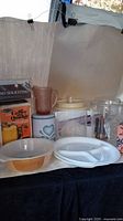 Overview of all kitchen items displayed on a table including plates, canisters, sign, casserole, and glassware.