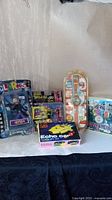 Photo of various new in box collectible figures and toys displayed on a white surface against a beige wall.