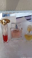 Photo of three perfume bottles on a white surface showing the lot contents and details of bottles
