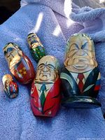 Five hand-painted wooden nesting dolls depicting Soviet politicians with detailed facial features and symbolic decorations on a blanket.
