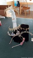 Photo showing all six metal tiaras and hairbands on a table and a mannequin hand with one tiara displayed.