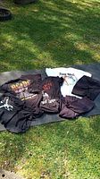 Full display of 4 graphic T-shirts, black shorts, and black flared activewear pants laid on outdoor surface.