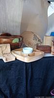 Wide shot showing several wooden items including large decorative bowl, smaller tray, divot tray with ceramic bowls, and carved wooden boxes.